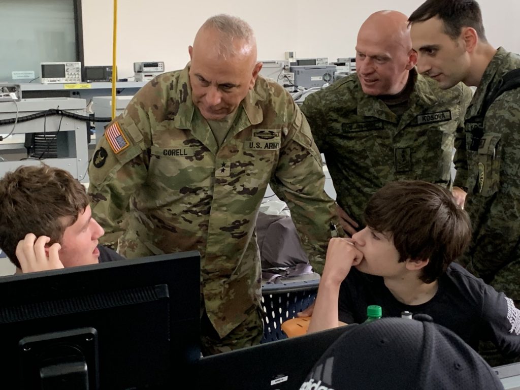 Waterloo (Iowa) Career Center high school students Beau Smith of Hudson and Schmitz of Cedar Falls brief Iowa National Guard commander Maj. Gen. Ben Corell and Kosovo Security Force commander Lt. Gen. Bashkim Jashari during the first International Cyberspace Security Exercise, conducted simultaneously on May 18, 2022, at Iowa State University (Ames, Iowa) and the University of Pristina, Kosovo. Photo by Randy Brown